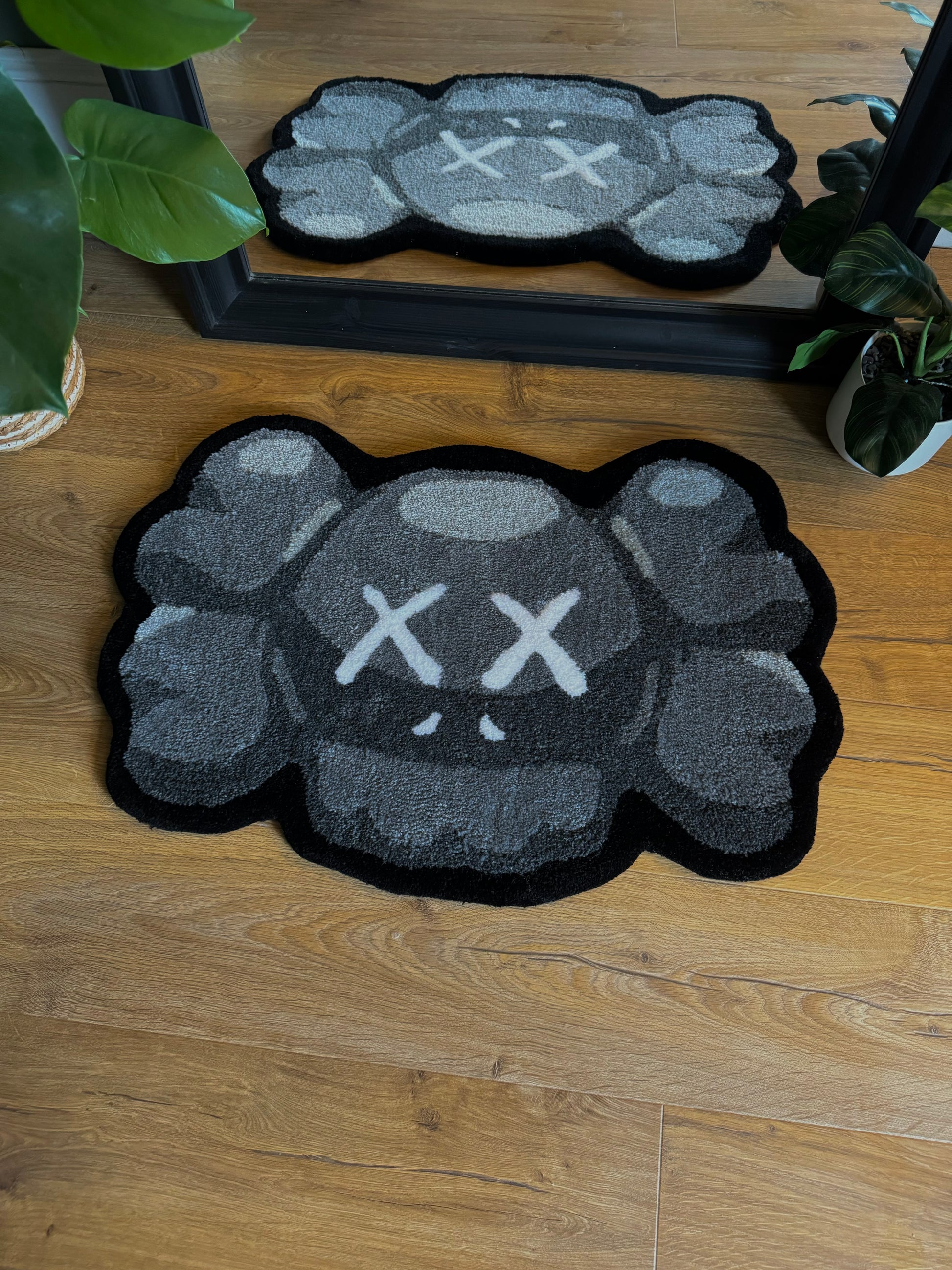 A handmade KAWS face tufted rug with a gray and black color scheme, featuring a stylized character face.